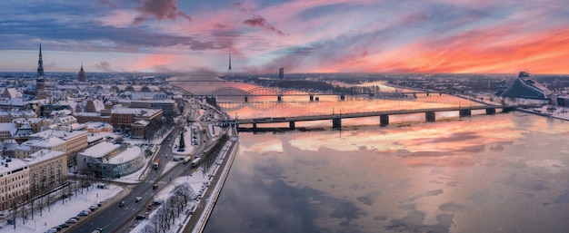 Panoramic shot of beautiful sunset over snow-covered Riga town with Daugava river and downtown