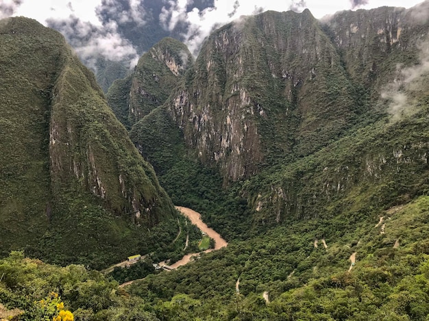 Free photo panoramic shot of a brown river in the middle of the green mountains of the majestic machu picchu