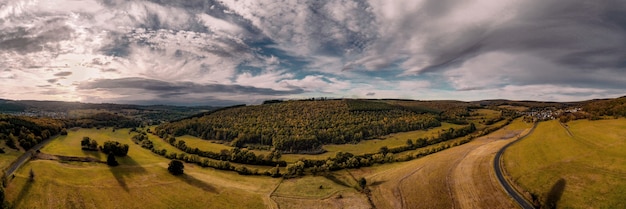 Free Photo panoramic shot of farm fields under the sunlight and a cloudy sky in the countryside