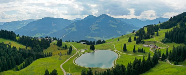 Free Photo panoramic shot of the filzalmsee surrounded by hills covered in greenery in austria