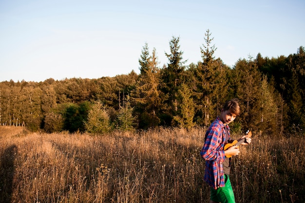 Free photo panoramic view of forest and man playing ukulele