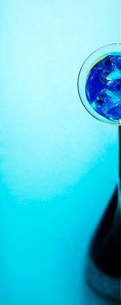 Free photo panoramic view of martini glass with ice cubes on blue backdrop