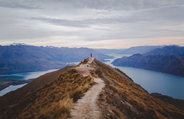 Panoramic view of the Roys Peak in New Zealand with low mountains in the distance under cloudscape