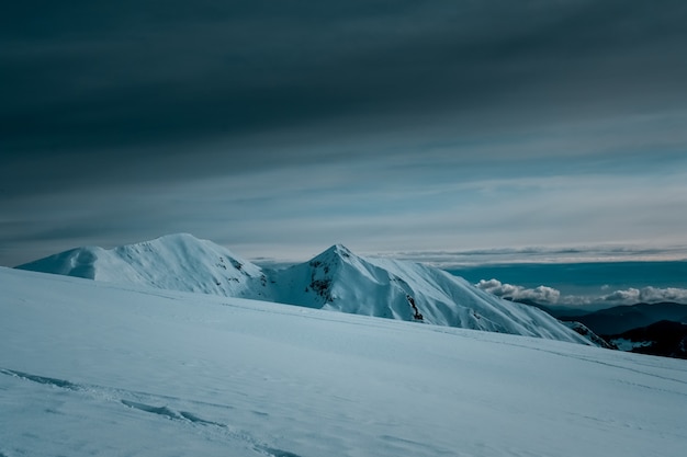 Panoramic view of snow covered mountains touching the clouds