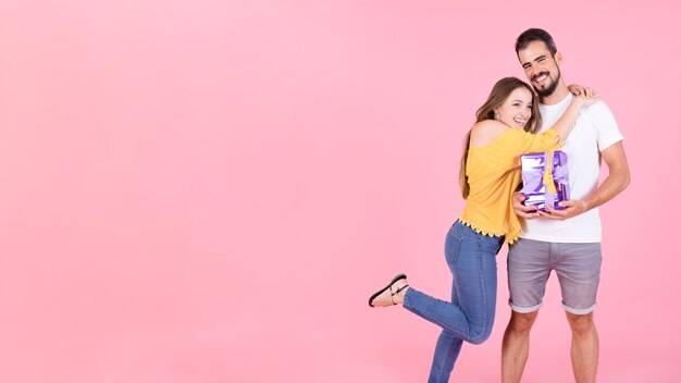 Panoramic view of woman hugging her boyfriend holding gift box