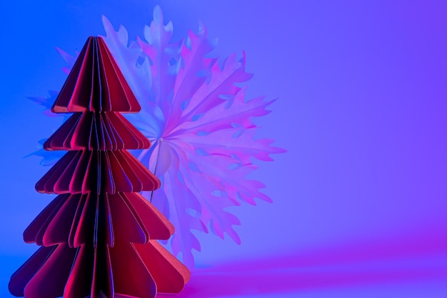 Free photo paper christmas tree and snowflake on neon gradient background