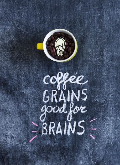 Paper cutout light bulb inside the coffee beans in the mug with text on chalkboard