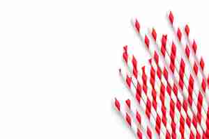 Free photo paper drinking straws with red stripes ornament on a white background flat lay