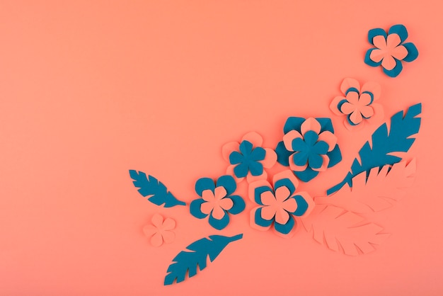 Paper flowers and leaves on coral background