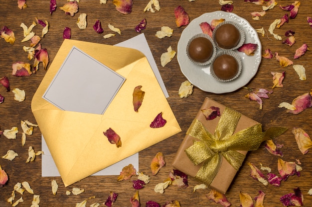 Free photo paper in letter near plate with candies and present box between dry leaves