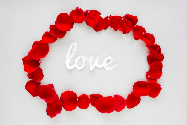 Free photo paper love inscription with rose petals on grey table