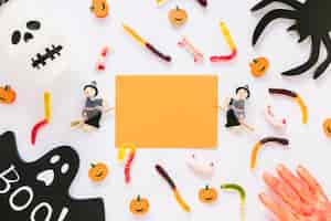 Free photo paper sheet with halloween decorations and candies with bloody hand