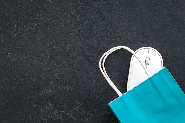 Free Photo paper shopping bag and computer mouse on a dark background top view