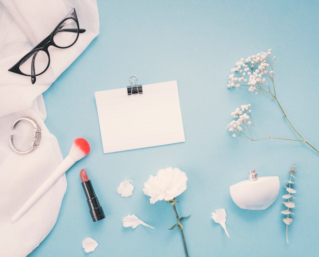 Paper with flowers and cosmetics on table