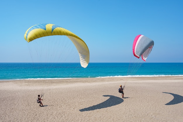 Free photo paraglider tandem flying over the sea shore with blue water and sky on horison. view of paraglider and blue lagoon in turkey.