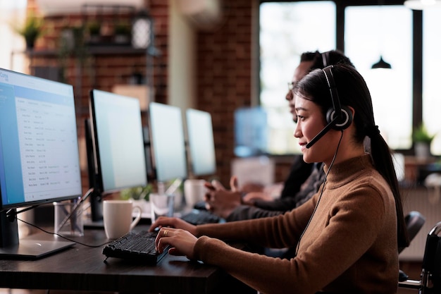 Free Photo paralyzed asian employee working at call center reception in disability friendly office. female operator wheelchair user with impairment giving assistance on customer service helpline.