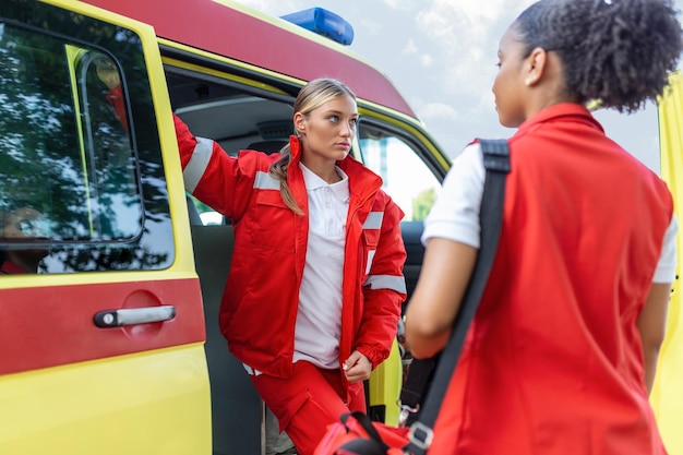 Paramedic nurse and emergency doctor at ambulance with kit a paramedic standing at the rear of an ambulance by the open doors