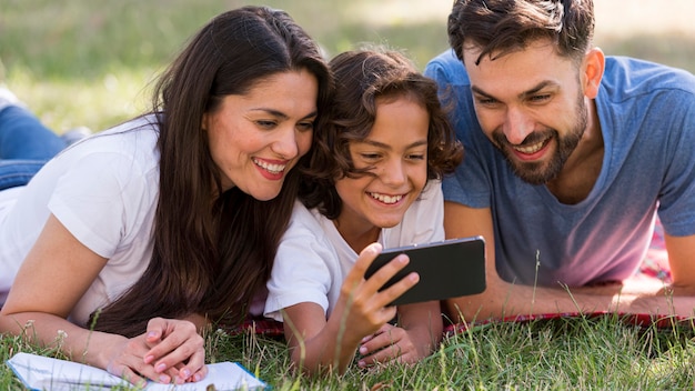 Parents and child watching something on smartphone while at the park