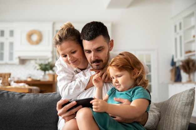 Parents and kid with device medium shot