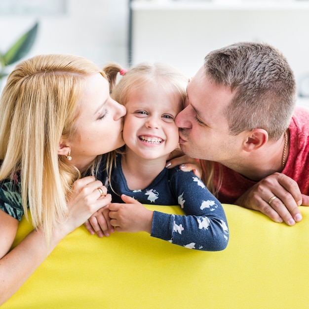 Free photo parents kissing to their little daughter