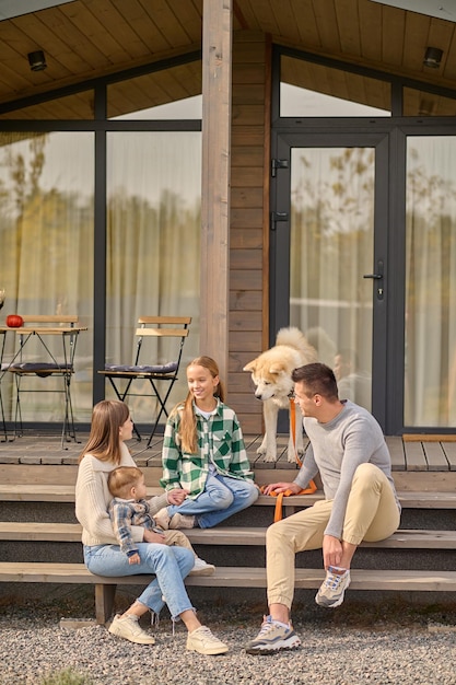 Free Photo parents looking at their daughter communicating on steps of house