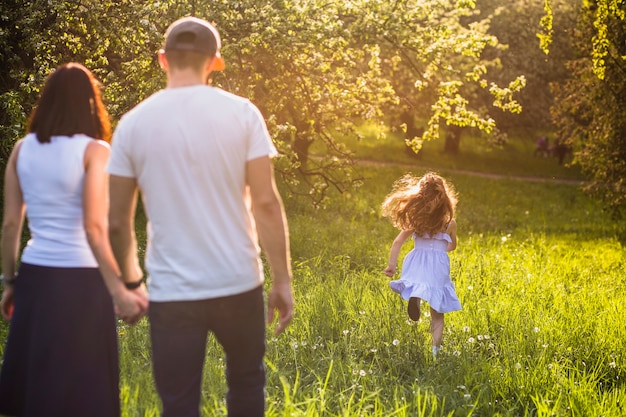 Parents looking at their girl child running in park