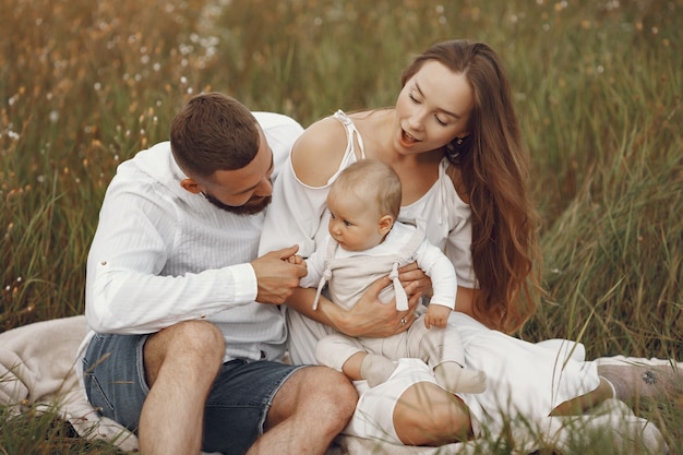 Parents with daughter. Family in a field. Newborn girl. Woman in a white dress.