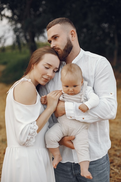 Parents with daughter. Family in a field. Newborn girl. Woman in a white dress.