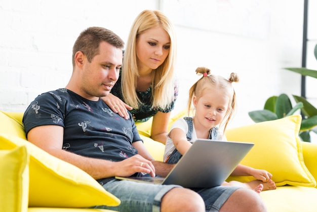 Free photo parents with little daughter using laptop in living room at home