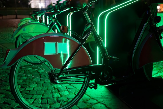 Free photo parked bicycles for sharing with green illuminationt night in bucharest, romania