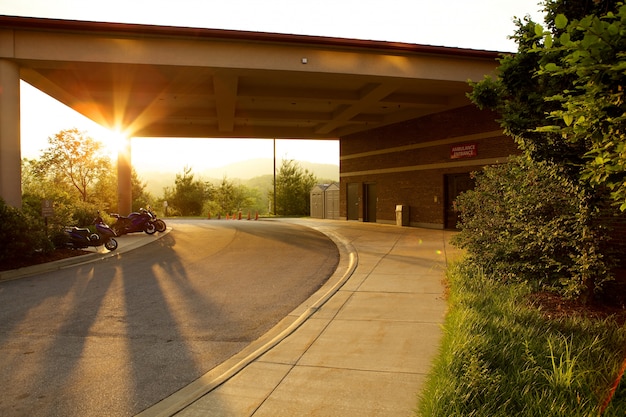 Parking place surrounded by greenery and motorcycles during the sunset