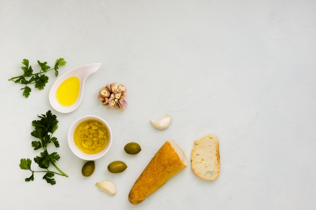 Free Photo parsley leaves; olive oil; garlic and bread on white textured backdrop