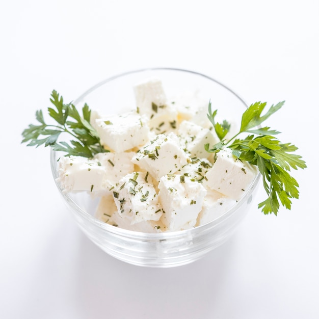 Free photo parsley with cheese cubes in the glass bowl against white background