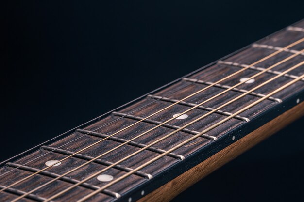 Part of an acoustic guitar, guitar fretboard on a black background.