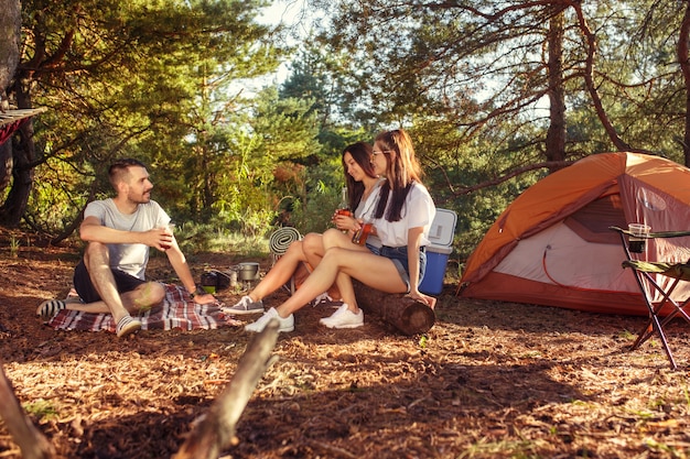 Party, camping of men and women group at forest. They relaxing against green grass. concept