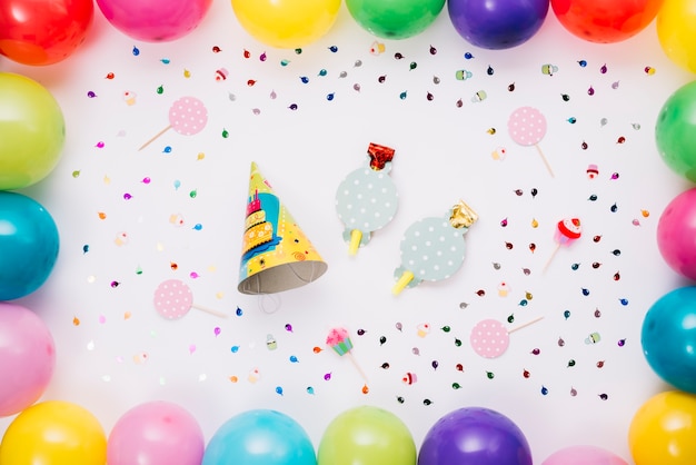 Free photo party hat and horn blower decorated with colorful balloons and confetti isolated on white backdrop