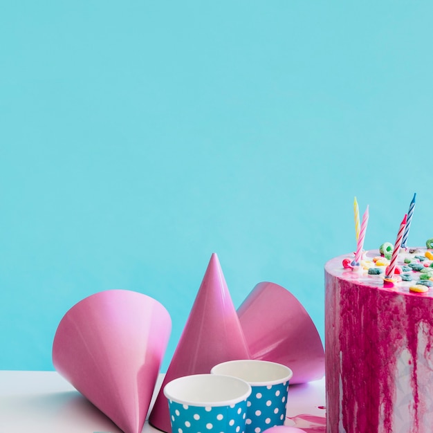 Party hats and cups near cake