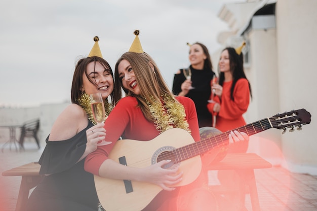 Free Photo partying women playing the guitar on the rooftop party