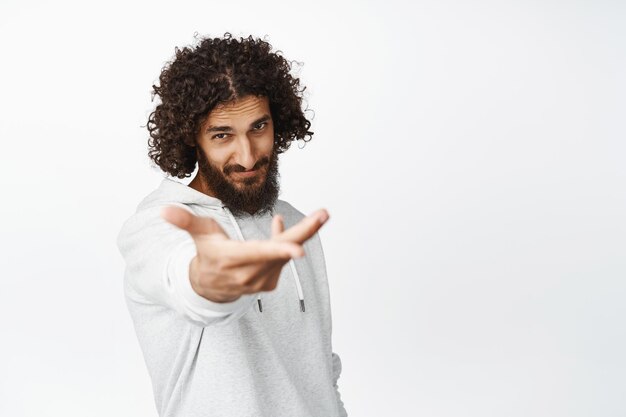 Passionate handsome hispanic man romantic extend his hand inviting for dance giving you something in his palm white background