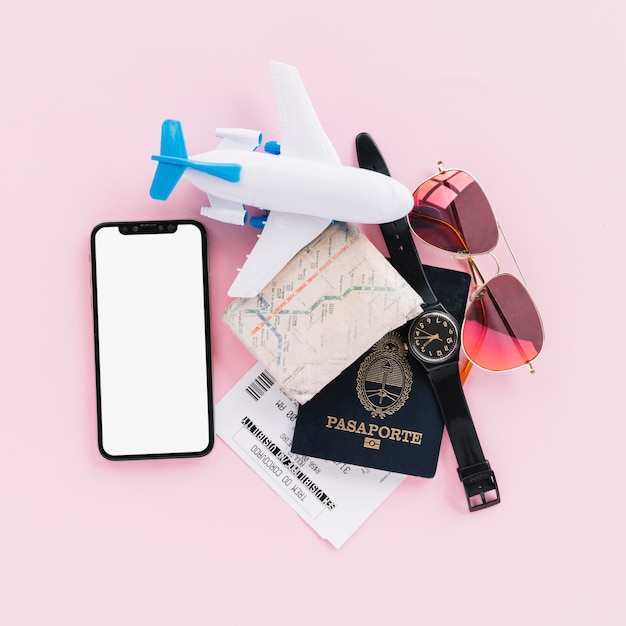 Free photo passport; map; tickets; toy airplane; wrist watch; mobile phone and sunglasses on pink background