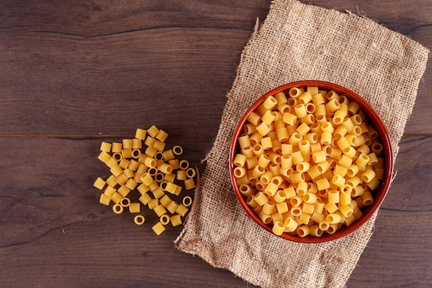 pasta in brown bowl on sackcloth on wooden surface