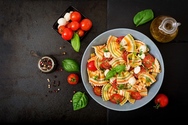 Pasta colored farfalle salad with tomatoes, mozzarella and basil.