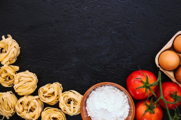 Pasta and flour near tomatoes and eggs