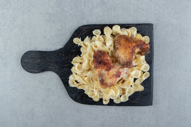 Free photo pasta and grilled chicken on black board.