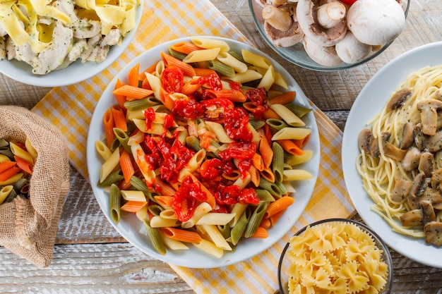 Pasta meals in plates with raw pasta, mushrooms