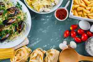 Free photo pasta meals with raw pasta, tomato, flour, mushroom, eggs, spice, spoon in plates