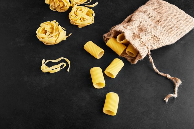 Pasta rolls and penne isolated on black.