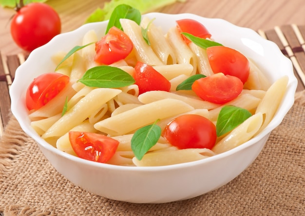 Pasta salad with cherry tomatoes and fresh basil leaves