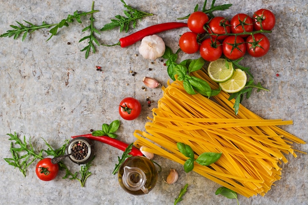 Free Photo pasta tagliatelle and ingredients for cooking (tomatoes, garlic, basil, chili). top view