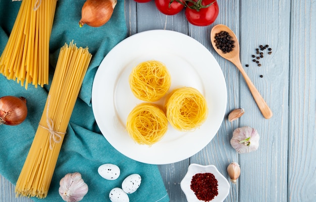 Pasta tagliolini on the white plate linguini spaghetti eggs garlic onion top view